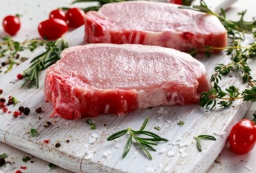 Raw,Pork,Loin,Chops,On,A,Cutting,Board,With,Herbs,